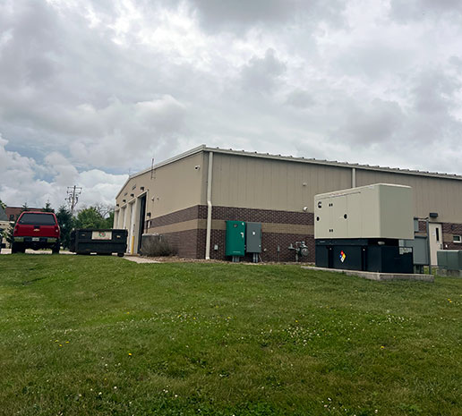 A generator system installed near a large garage-style building